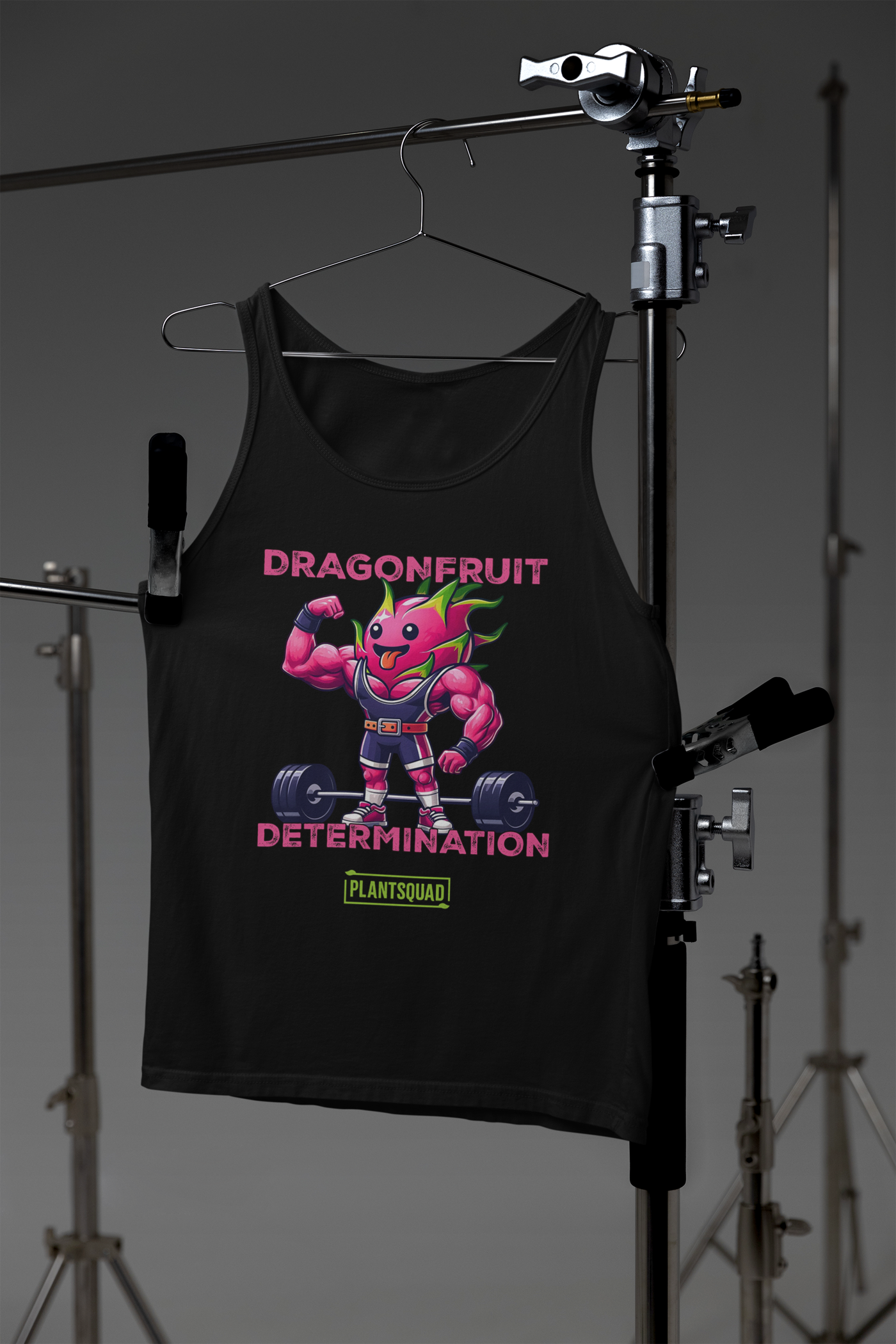 The Plantsquad Dragonfruit "Dragonfruit Determination" - Unisex Tank Top is a sleeveless black tank, showcasing a muscular, anthropomorphic dragon fruit character in a bodybuilding pose. Perfect for intense training sessions, it features "DRAGONFRUIT DETERMINATION" above and below the character, with a "PLANTSQUAD" logo at the bottom.