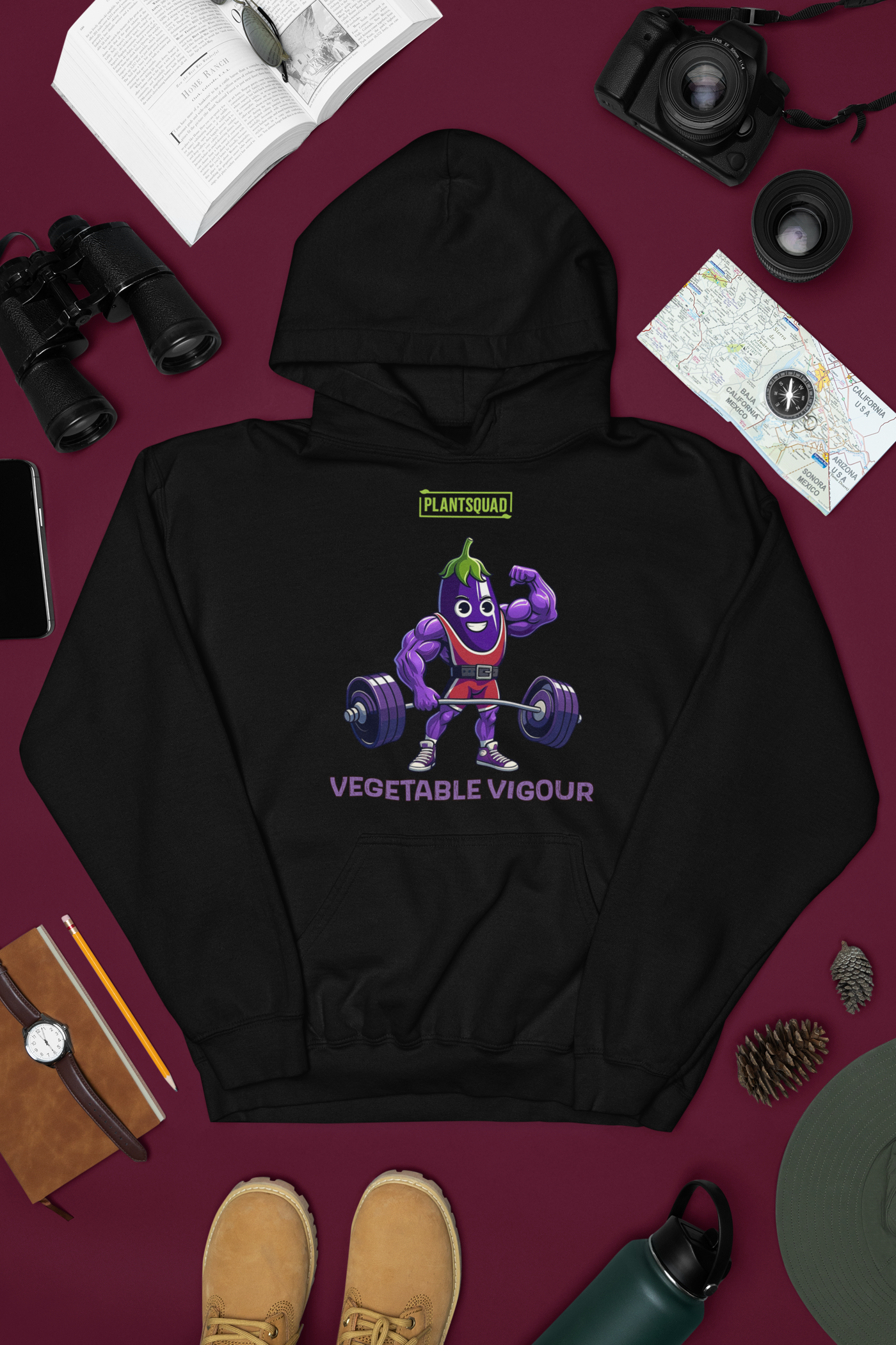 The Plantsquad Eggplant "Vegetable Vigour" - Unisex Hoodie features an illustration of a muscular cartoon vegetable lifting weights. The character is smiling and flexing one arm. The text above reads "PLANT SQUAD," and below, it says "VEGETABLE VIGOUR." Perfect for embracing the vegan lifestyle with its fun, weight-lifting theme.