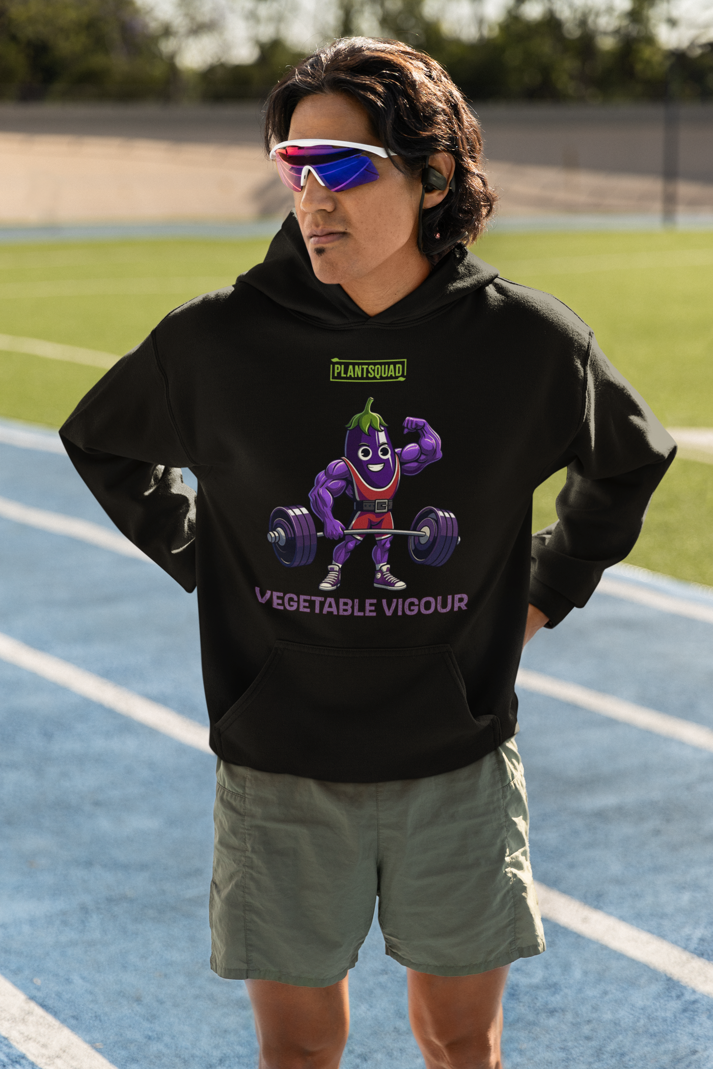 The Plantsquad Eggplant "Vegetable Vigour" - Unisex Hoodie features an illustration of a muscular cartoon vegetable lifting weights. The character is smiling and flexing one arm. The text above reads "PLANT SQUAD," and below, it says "VEGETABLE VIGOUR." Perfect for embracing the vegan lifestyle with its fun, weight-lifting theme.