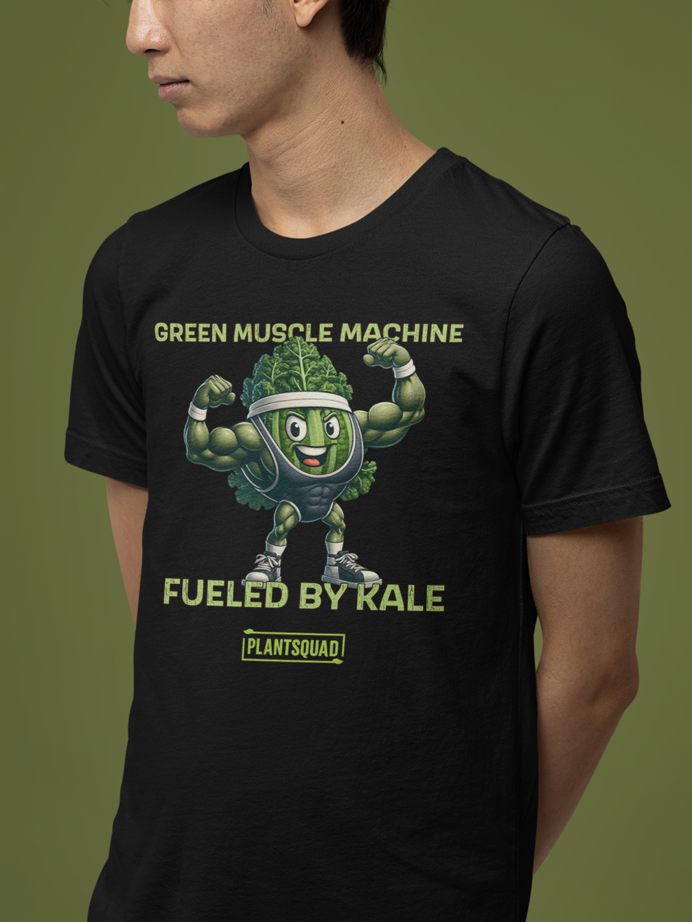 Plantsquad Kale "Green Muscle Machine Fueled By Kale" - Unisex T-Shirt featuring a cartoon kale character with muscular arms, flexing and smiling. The shirt displays the text "GREEN MUSCLE MACHINE" above the character and "FUELED BY KALE" below. Proudly wear your "PLANTSQUAD" mantra at the bottom of this unique design.
