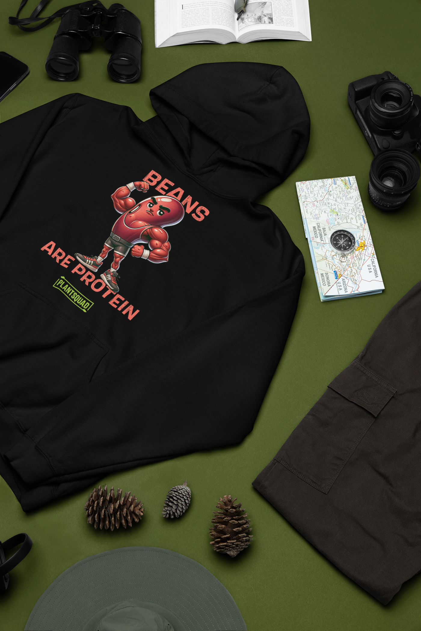 A black hoodie featuring a graphic of a muscular, anthropomorphic bean character in boxing gear, with the text "Beans Are Protein" in bold red letters above and below the image. Embrace your vegan lifestyle with this Plantsquad Kidney Bean "Beans Are Protein" - Unisex Hoodie. Below the text is a small green rectangle with the word "PLANTSQUAD.