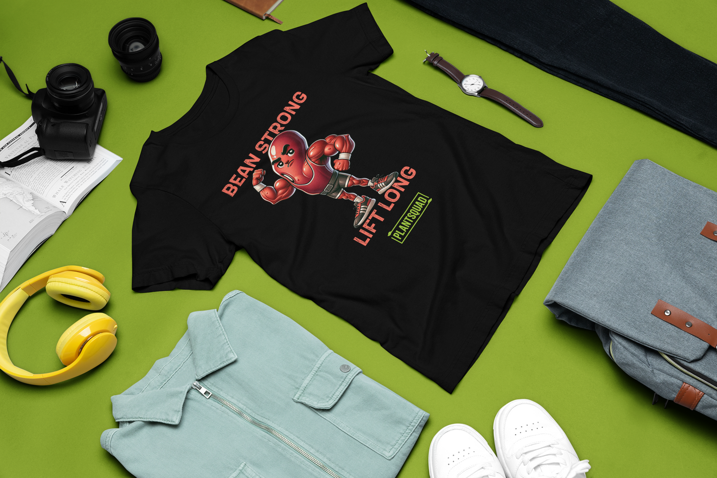 A black t-shirt featuring a muscular cartoon bean character flexing its arm. Above the character are the words "BEAN STRONG" and below it, "LIFT LONG." The bottom of this Plantsquad Kidney Bean "Bean Strong Lift Long" - Unisex T-Shirt proudly displays the "PLANTSQUAD" logo.