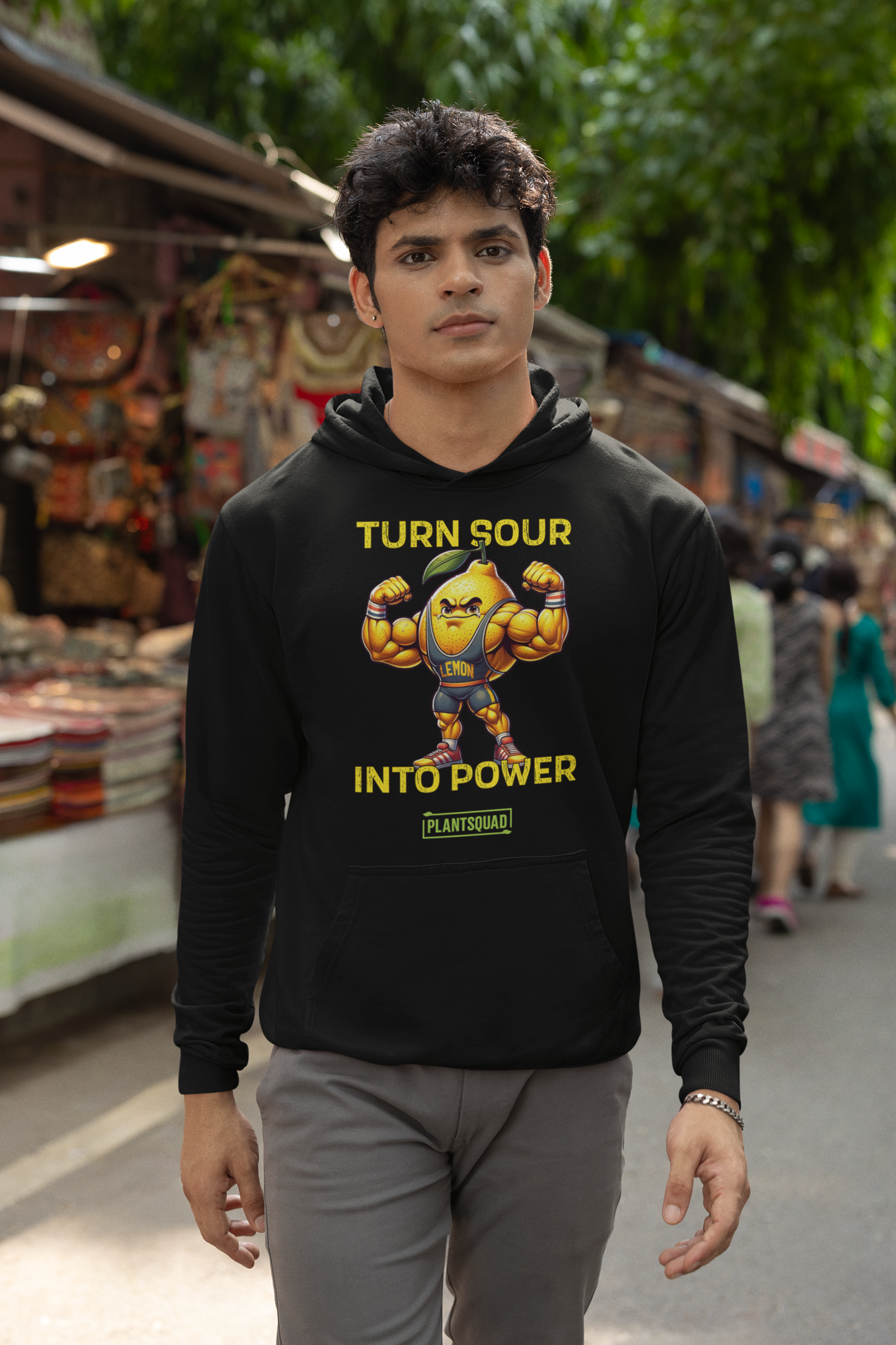 A Plantsquad Lemon "Turn Sour Into Power" - Unisex Hoodie featuring a muscular, animated lemon character flexing its arms. The text above the lemon reads "TURN SOUR," and the text below reads "INTO POWER." The word "LEMON" is on the character's chest. The bottom text reads "PLANTSQUAD," perfect for your vegan gym wear collection.