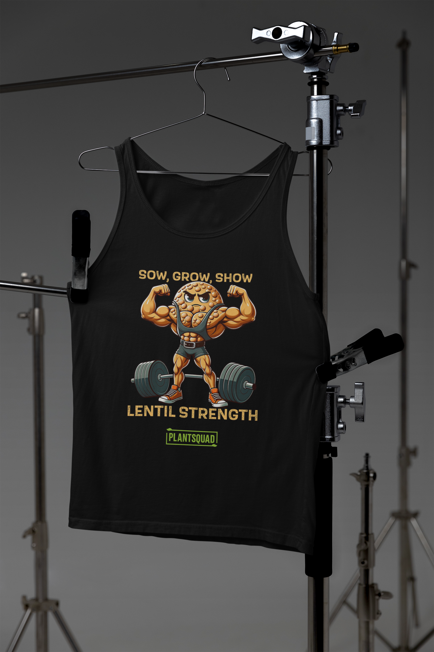 A black Plantsquad Lentil "Sow Grow Show Lentil Strength" - Unisex Tank Top featuring a cartoon lentil character with muscular arms lifting a barbell. The text above reads "Sow, Grow, Show" and below, "Lentil Strength." At the bottom, there's a green PLANTSQUAD logo. Perfect for those embracing a vegan lifestyle.