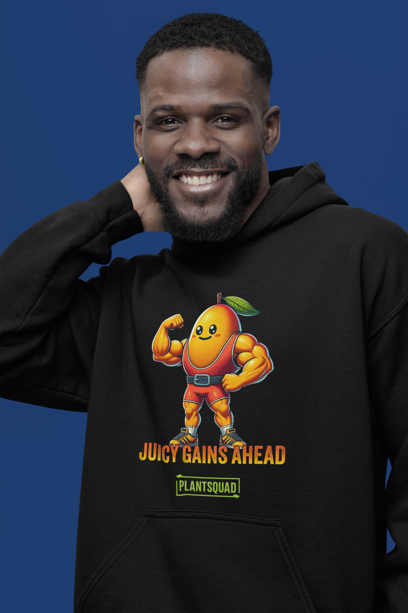 A black Plantsquad Mango "Juicy Gains Ahead" - Unisex Hoodie features a muscular mango cartoon flexing its biceps, donning a green leaf on its head. Below the mango, the text reads "Juicy Gains Ahead" in bold orange letters and "Plant Squad" in a green rectangular box, perfect for showcasing your vegan lifestyle.