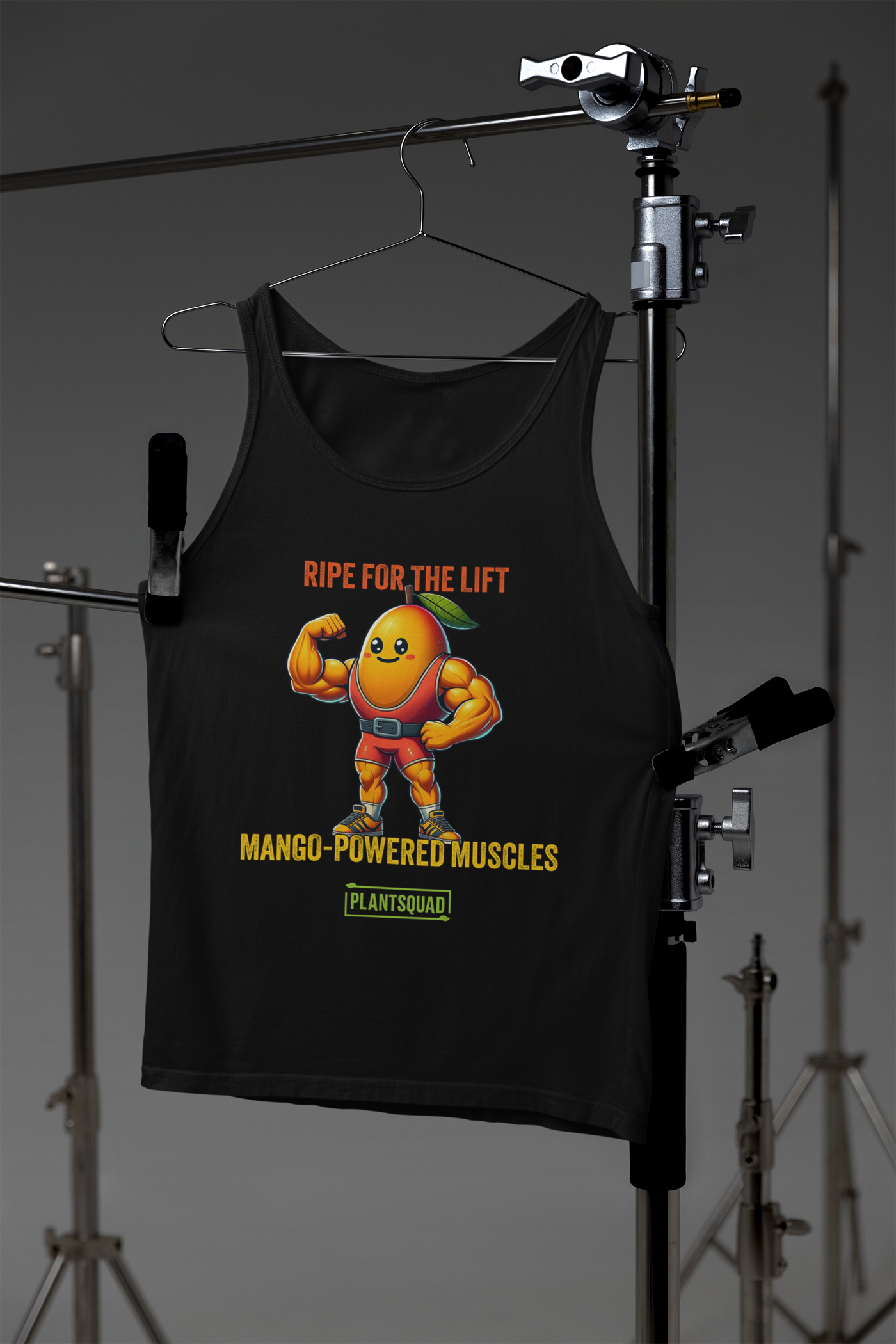 Graphic on a Plantsquad Mango "Ripe For The Lift Mango-Powered Muscles" - Unisex Tank Top featuring a muscular, anthropomorphic mango flexing its arms. The text above the mango reads, "RIPE FOR THE LIFT," and below it reads, "MANGO-POWERED MUSCLES." Designed for gym enthusiasts embracing a plant-based lifestyle, the breathable fabric ensures comfort. The logo at the bottom says "PLANTSQUAD.