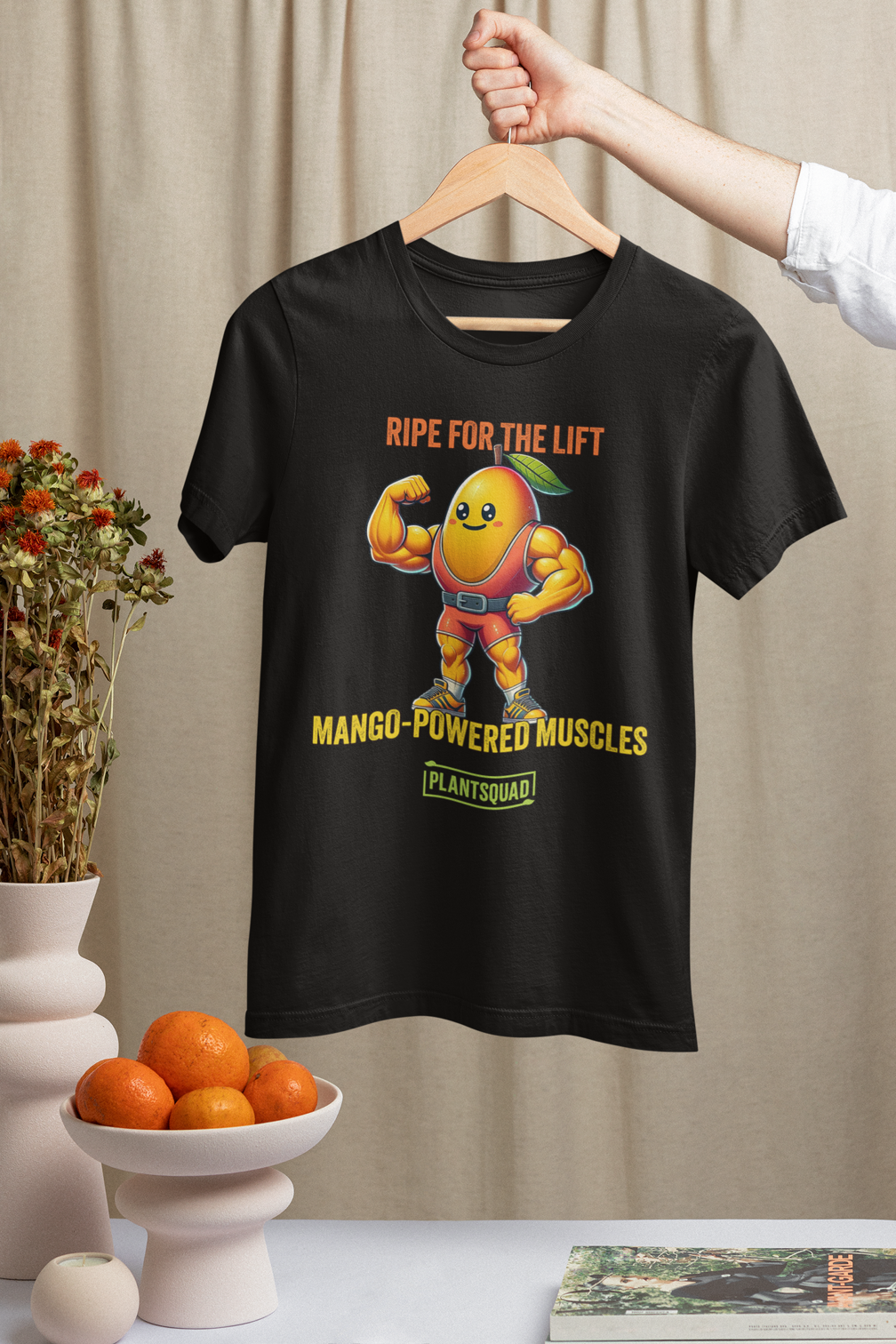 Plantsquad Mango "Ripe For The Lift Mango-Powered Muscles" - Unisex T-Shirt featuring a muscular cartoon mango character flexing its bicep. Above the character, the text reads "RIPE FOR THE LIFT," and below, "MANGO-POWERED MUSCLES." Perfect for fitness enthusiasts who embrace a vegan lifestyle. At the bottom, a green rectangle with "PLANTSQUAD" is displayed.