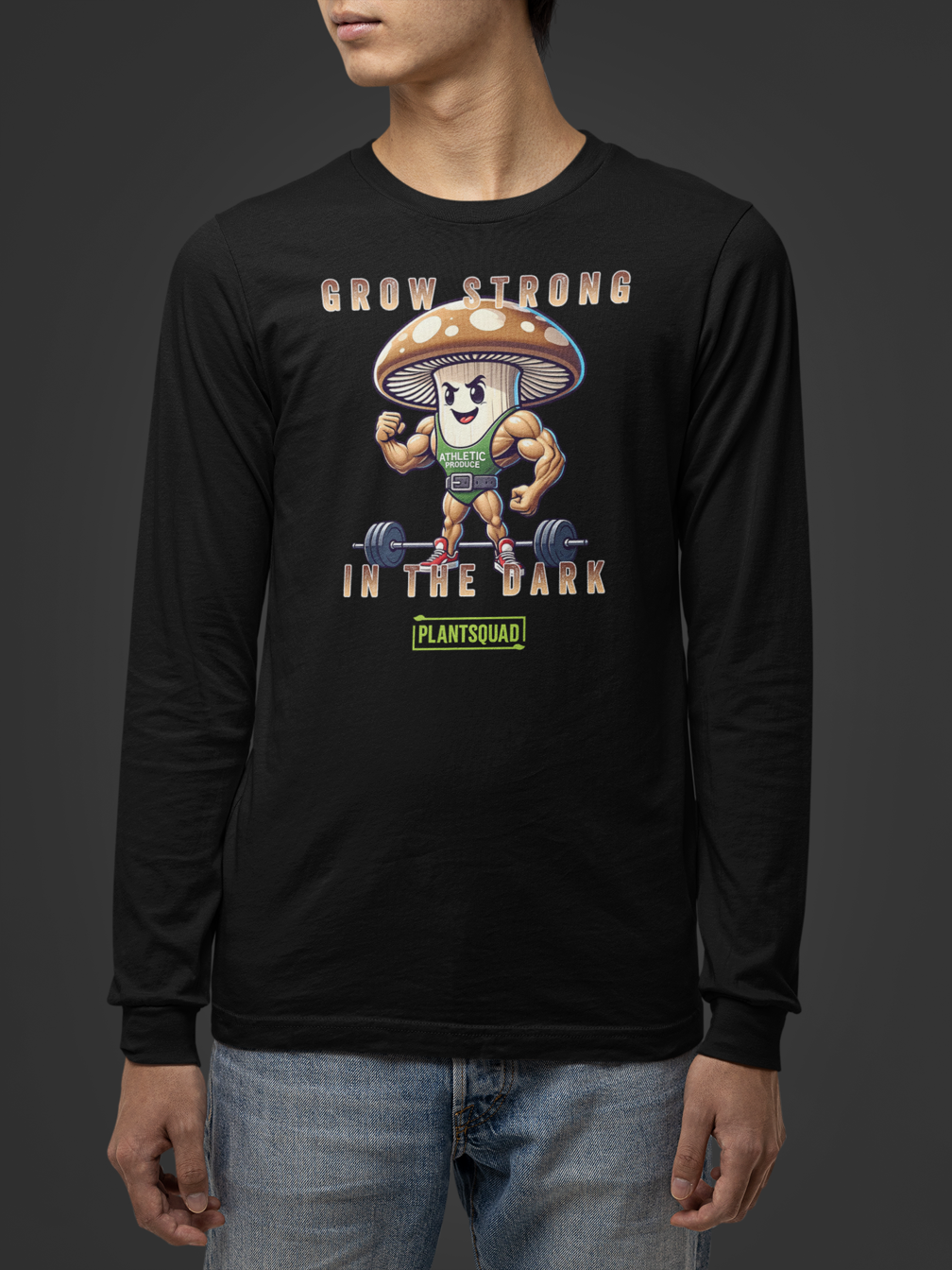 A Plantsquad Mushroom "Grow Strong In The Dark" - Unisex Long Sleeve T-Shirt with a muscly mushroom cartoon character lifting dumbbells. The text above reads, "GROW STRONG IN THE DARK," and below the character, it says, "PLANTSQUAD." Perfect for fitness enthusiasts who embrace a vegan lifestyle, the mushroom has a determined expression and flexes its muscles.