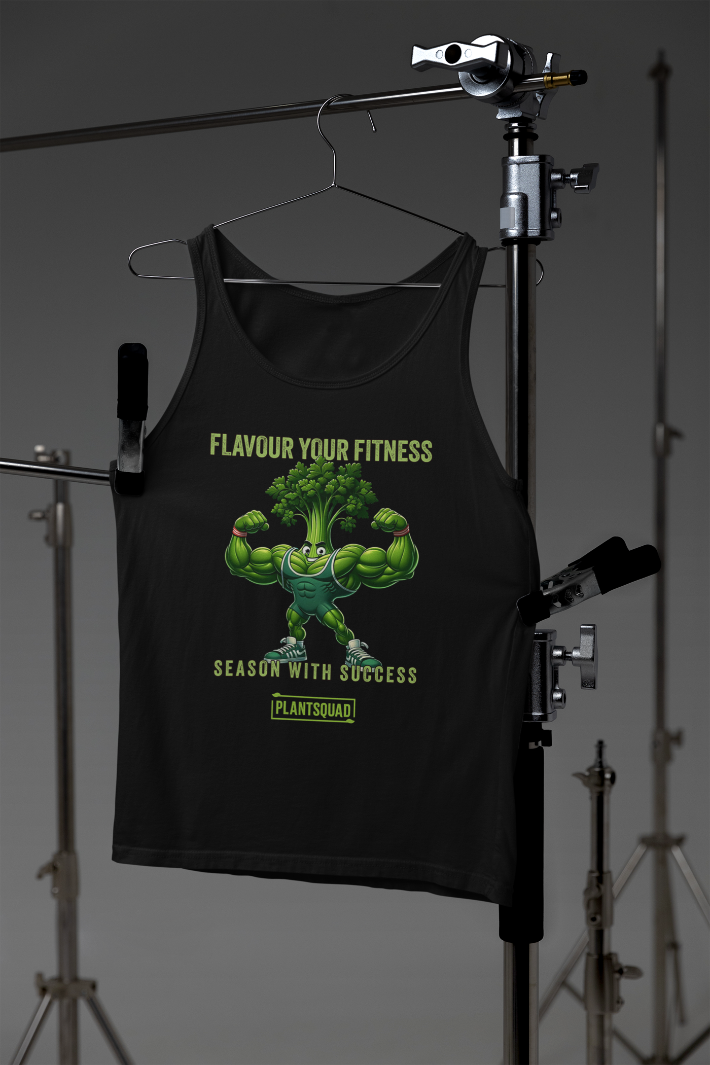 A black Plantsquad Parsley "Flavour Your Fitness Season With Success" - Unisex Tank Top featuring a cartoon image of a muscular broccoli flexing its arms. Above the broccoli, the text reads "FLAVOUR YOUR FITNESS" and below, it states "SEASON WITH SUCCESS." At the bottom, the text "PLANTSQUAD" is displayed. Perfect for your plant-based lifestyle or vegan gym wear collection.