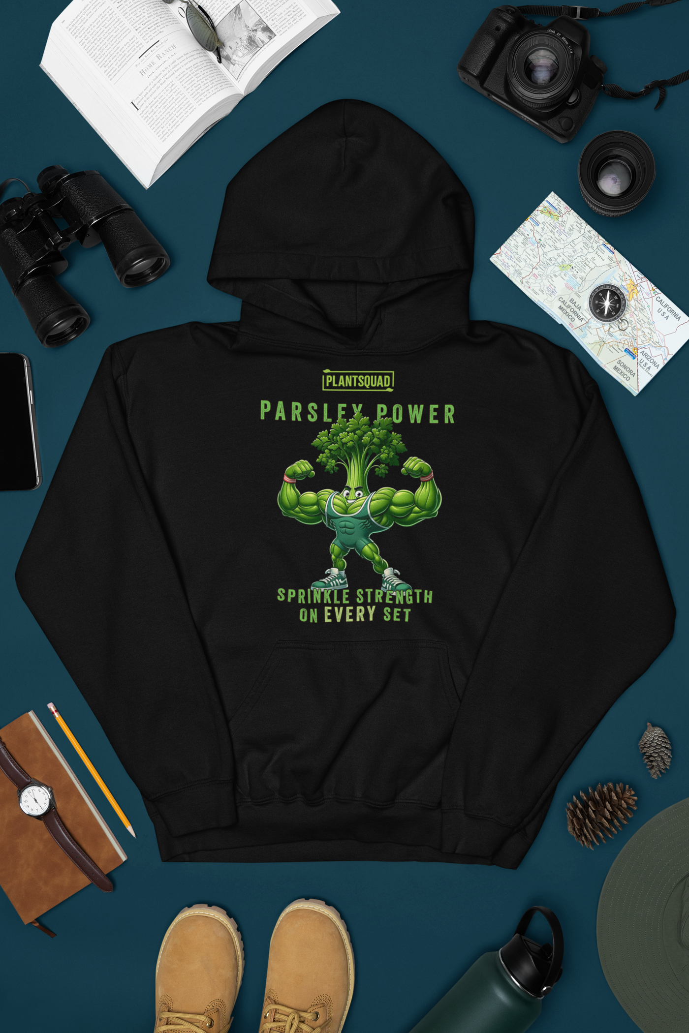 A black Plantsquad Parsley "Parsley Power Sprinkle Strength On Every Set" - Unisex Hoodie featuring a muscular cartoon parsley character flexing its arms. Above the character is the text "PLANTSQUAD" and "PARSLEY POWER." Below, it reads "SPRINKLE STRENGTH ON EVERY SET." The design is in shades of green and white, perfect for vegan gym apparel enthusiasts.