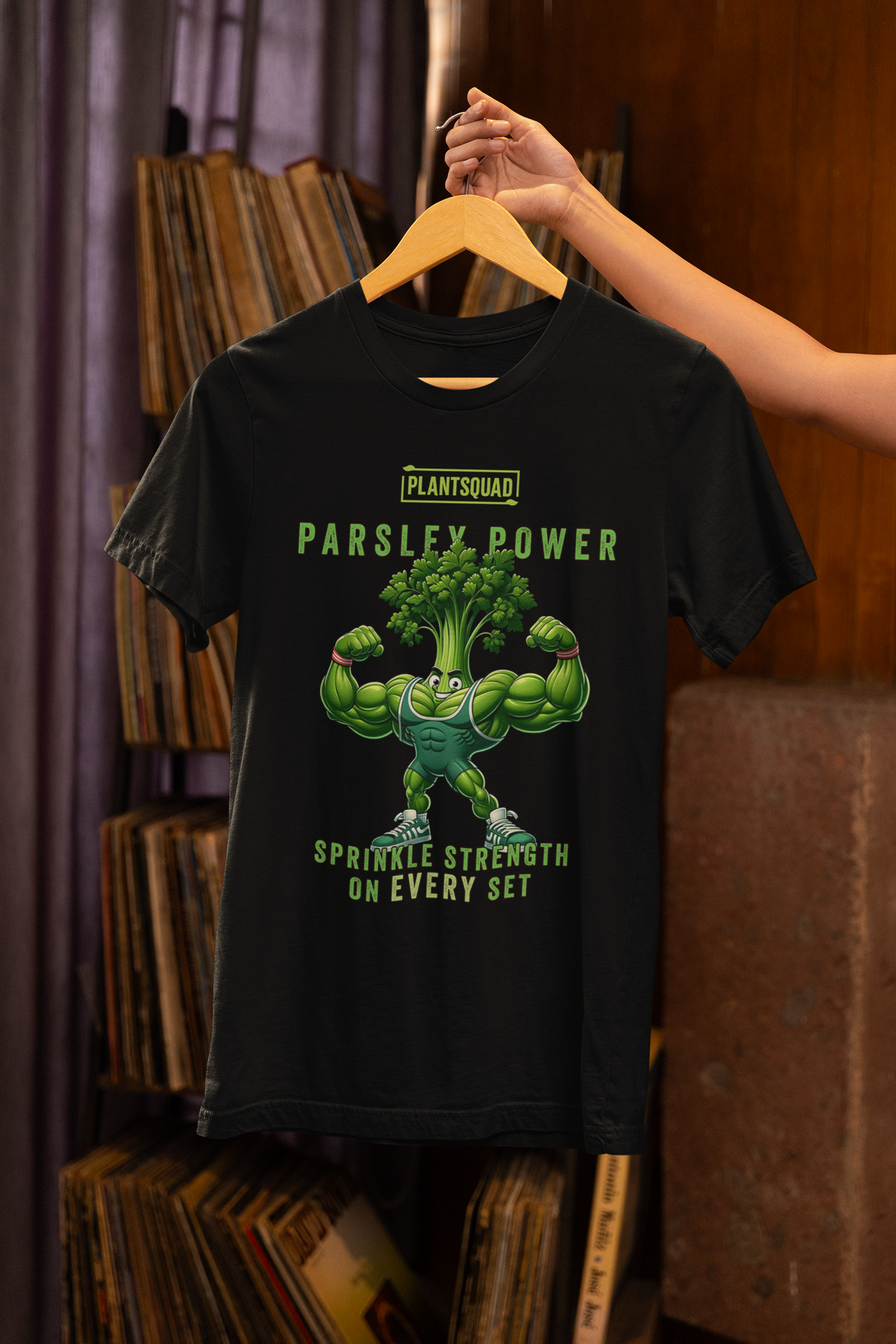 A black **Plantsquad Parsley "Parsley Power Sprinkle Strength On Every Set" - Unisex T-Shirt** featuring a muscular green cartoon parsley character flexing its arms, with the text “PLANTSQUAD PARSLEY POWER” above and “SPRINKLE STRENGTH ON EVERY SET” below it. Perfect for those embracing a vegan lifestyle!