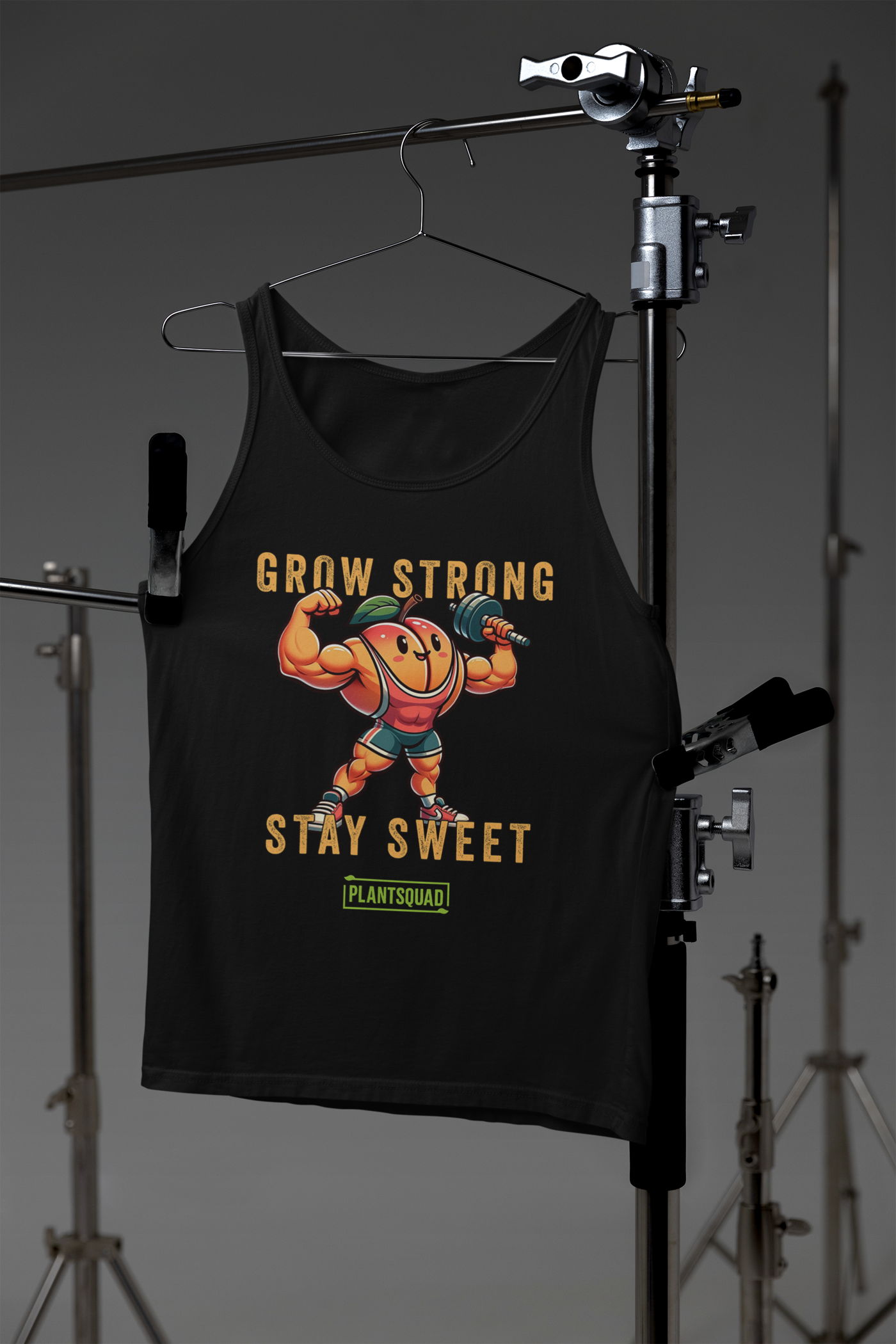 A black vegan workout tank top featuring an illustration of a muscular, happy anthropomorphic pumpkin lifting a dumbbell. The text above and below the pumpkin reads "Grow Strong Stay Sweet," with a green box at the bottom containing "PlantSquad." Perfect for showcasing your plant-based lifestyle! Introducing the Plantsquad Peach "Grow Strong Stay Sweet" - Unisex Tank Top.