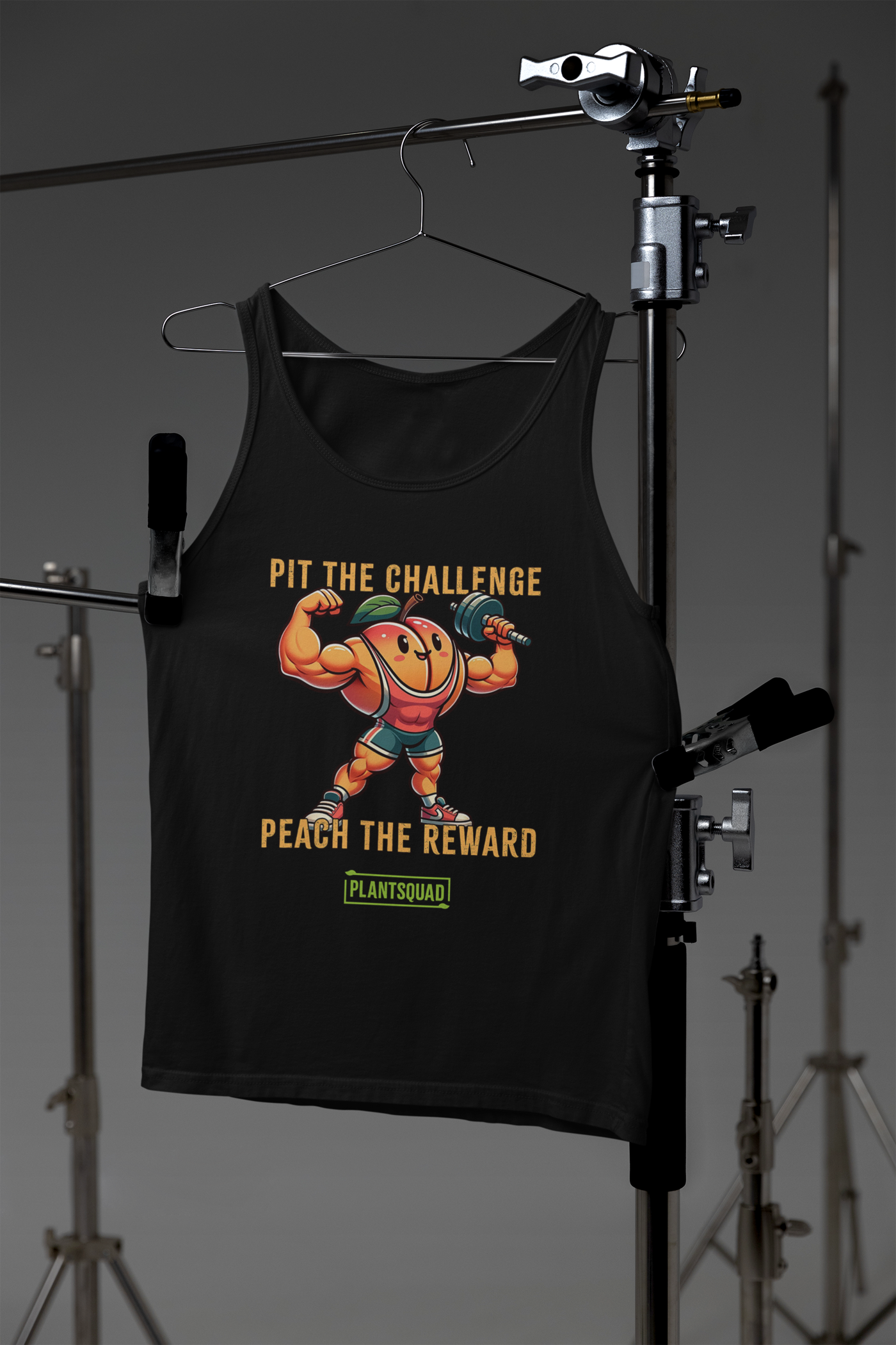 A black tank top featuring a muscly peach cartoon lifting a barbell. The text above the peach says "PIT THE CHALLENGE" and below it says "PEACH THE REWARD." Underneath, the word "PLANTSQUAD" is displayed on a green background, making it ideal vegan gym wear for those embracing a plant-based lifestyle. Plantsquad Peach "Pit The Challenge Peach The Rewards" - Unisex Tank Top