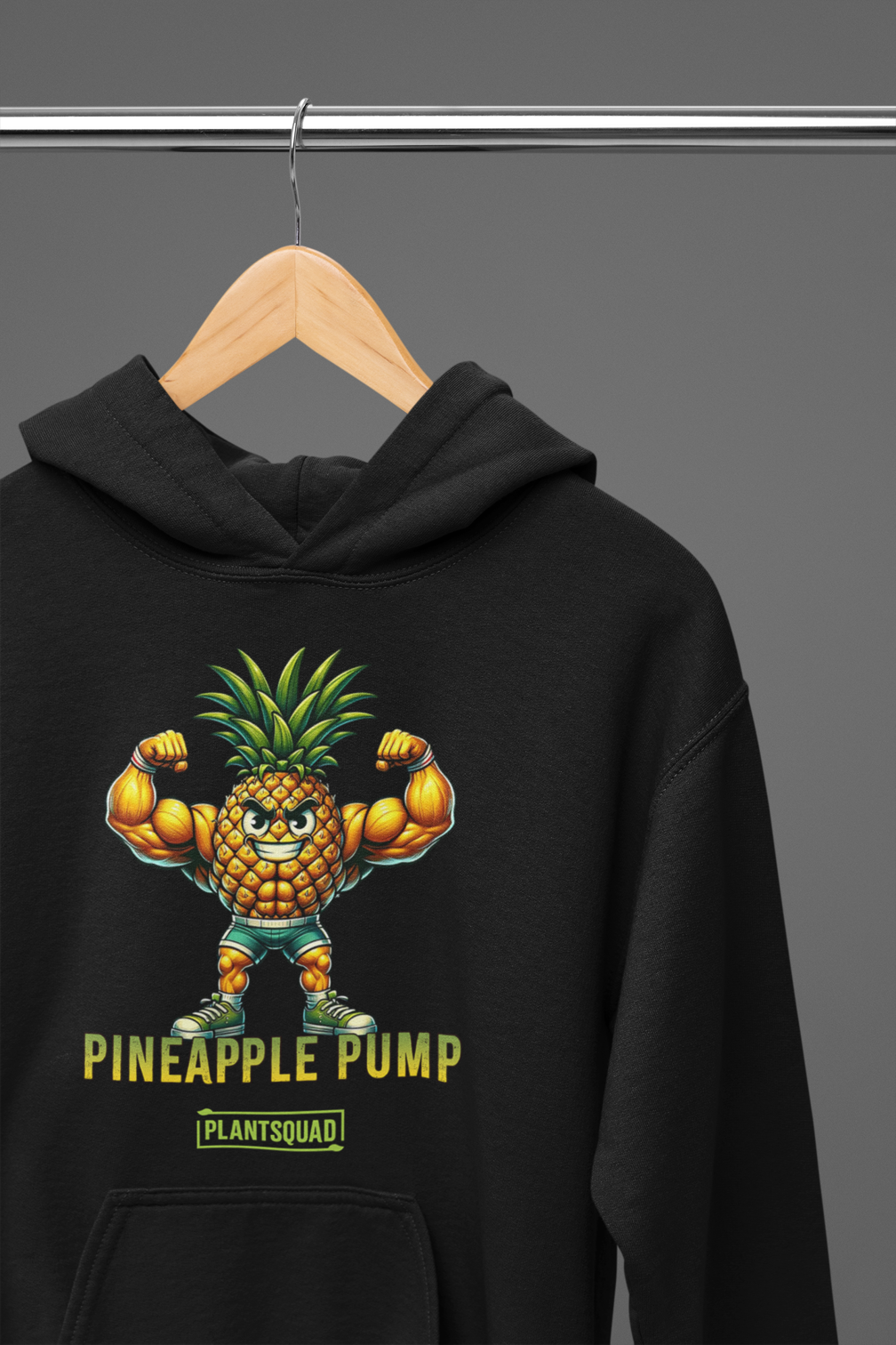 A black hooded sweatshirt features a muscular, anthropomorphic pineapple flexing its arms. Below the pineapple, the text reads "Pineapple Pump" with the brand name "PlantSquad" underneath. Perfect for gym enthusiasts embracing a vegan lifestyle, this Plantsquad Pineapple "Pineapple Pump" - Unisex Hoodie is both stylish and motivating.