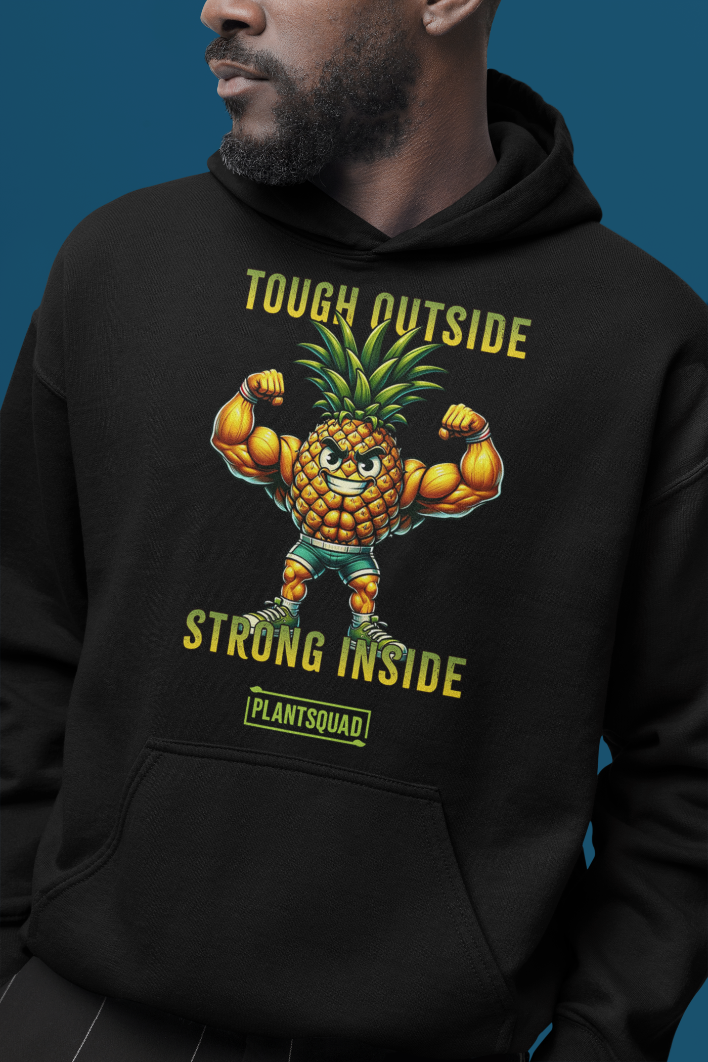 A cozy fabric black Plantsquad Pineapple "Tough Outside Strong Inside" - Unisex Hoodie featuring a muscular pineapple design with green leaves on its head. The pineapple flexes its muscles, with text above reading "Tough Outside," and below, "Strong Inside." Perfect for those embracing a vegan lifestyle, the word "PLANTSQUAD" is also proudly displayed.