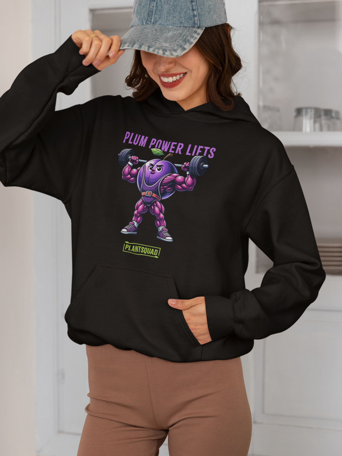 **Plantsquad Plum "Plum Power Lifts" - Unisex Hoodie** featuring a muscular cartoon plum character lifting barbells. Above the character, the text reads "PLUM POWER LIFTS" in purple letters. Below the character, the text reads "PLANT SQUAD" in green letters, perfect for those embracing a plant-based or vegan lifestyle.