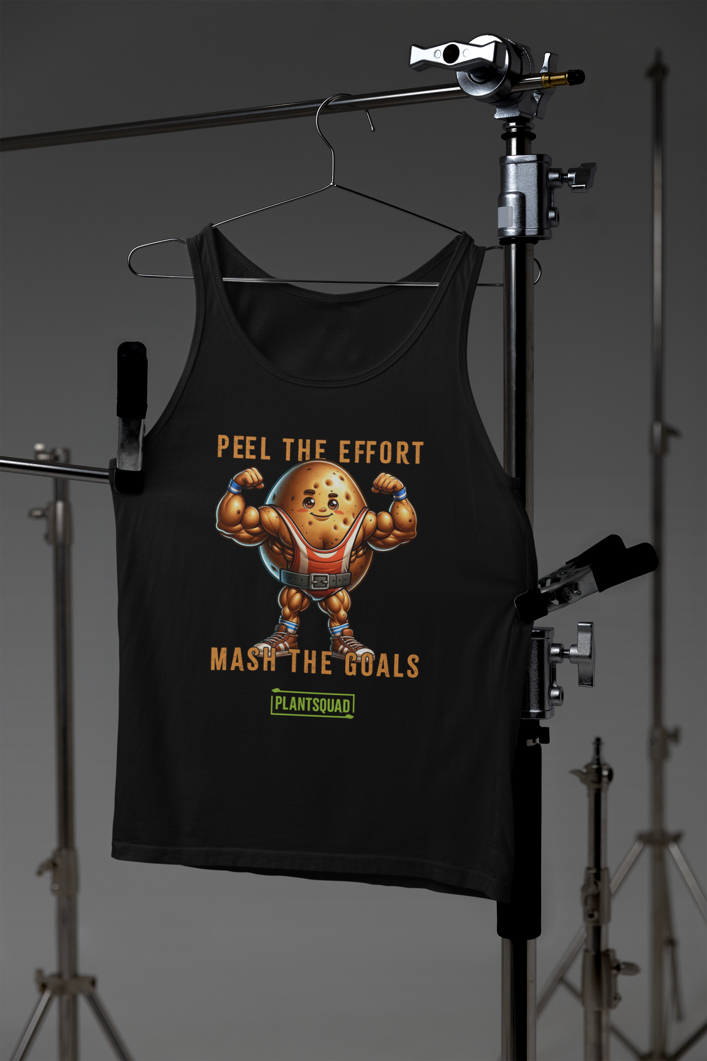 A Plantsquad Potato "Peel The Effort Mash The Goals" - Unisex Tank Top with a graphic of a muscly potato cartoon sporting muscular arms, wearing a belt, and flexing. Text reads "Peel the Effort" above and "Mash the Goals" below. A small "PlantSquad" logo is at the bottom. Perfect as plant-based gym apparel for your vegan workout routine.