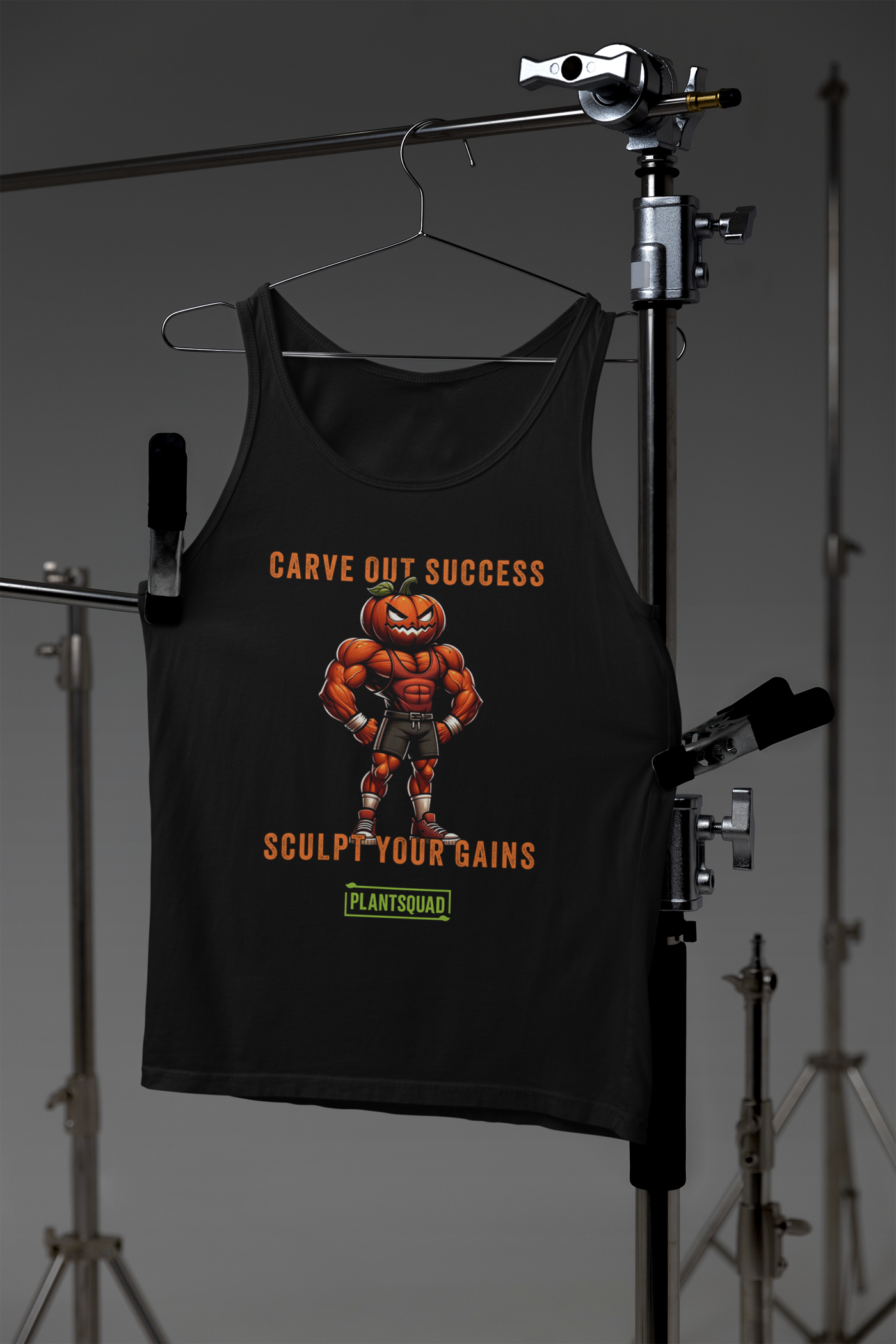 The Plantsquad Pumpkin "Carve Out Your Success Sculpt Your Gains" - Unisex Tank Top is a black vegan tank top featuring a muscular, anthropomorphic pumpkin lifting weights. Above the pumpkin, text reads "Carve Out Success." Below, text reads "Sculpt Your Gains." At the bottom is a green rectangular logo with the inscription "Plantsquad." Perfect for your next workout session.