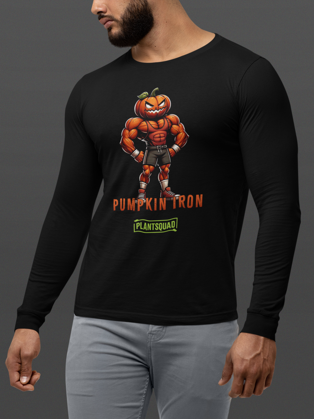 A black long-sleeve shirt features a muscly pumpkin cartoon character with a pumpkin head, wearing shorts and sneakers. The confident figure stands with fists on hips, perfect for fitness enthusiasts. The text "Plantsquad Pumpkin 'Pumpkin Iron' - Unisex Long Sleeve T-Shirt" is written below the character, followed by "PLANTSQUAD" in a green box.