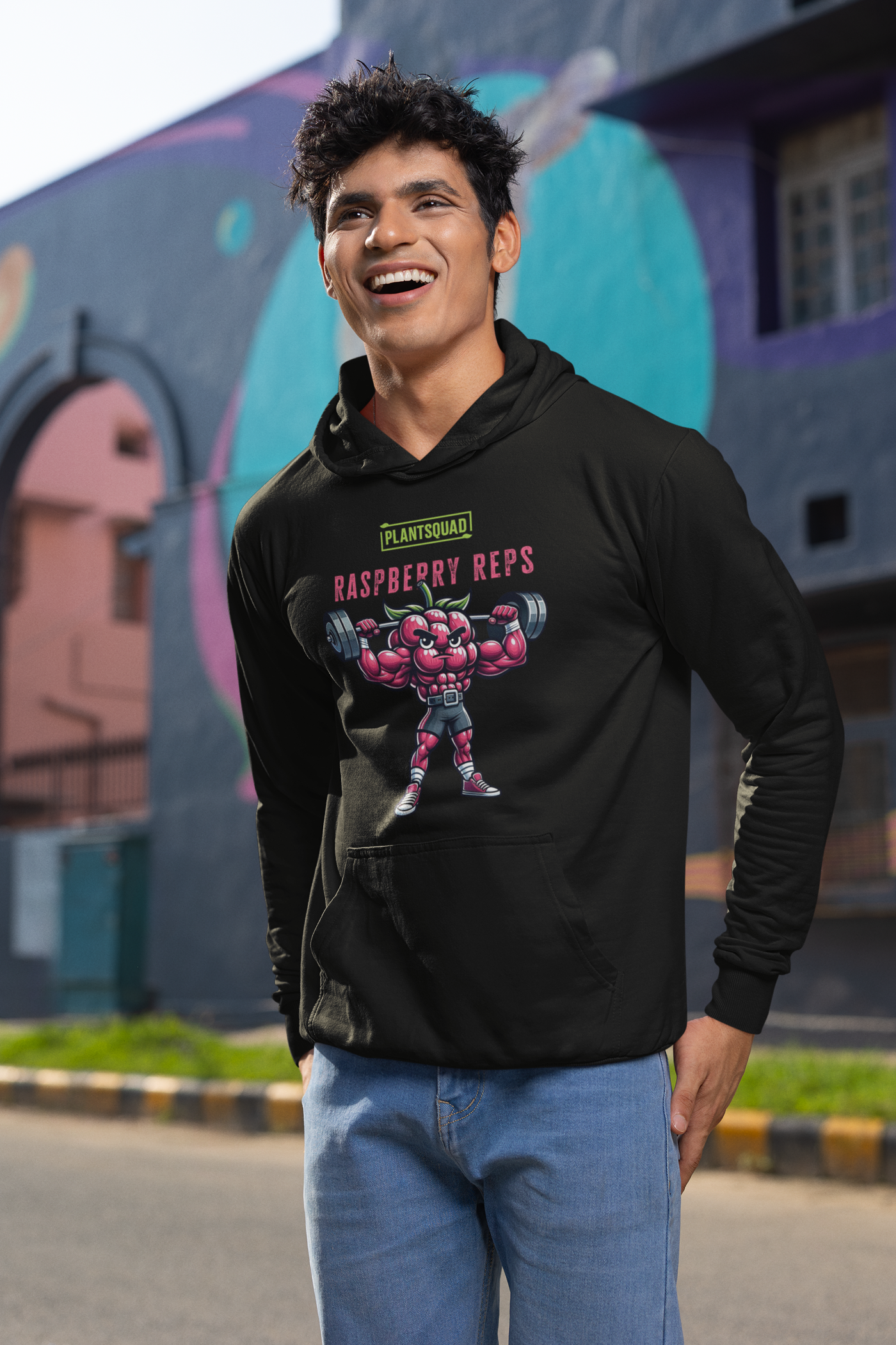 A black weight-lifting Plantsquad Raspberry "Raspberry Reps" - Unisex Hoodie featuring a muscular, animated raspberry character lifting a barbell. The text above the character reads "PLANTSQUAD" and below it says "Raspberry Reps." Perfect for gym enthusiasts embracing a plant-based vegan lifestyle, the design is colorful and playful, emphasizing fitness with a fun, fruity twist.