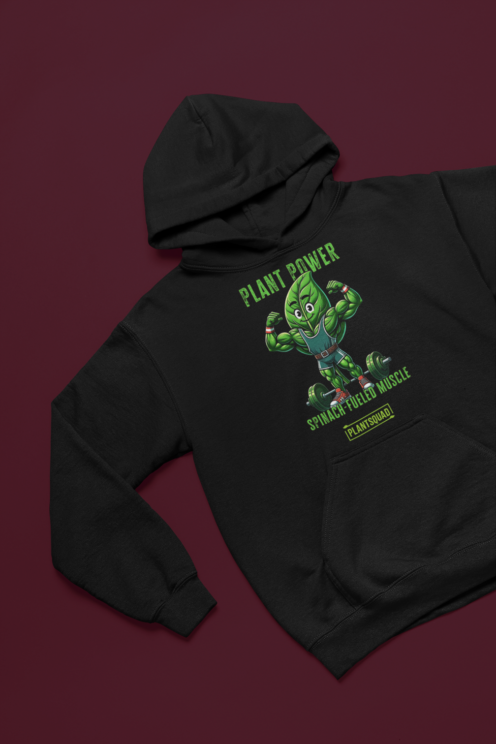 The Plantsquad Spinach "Plant Power Spinach Fueled Muscle" - Unisex Hoodie features a muscular cartoon spinach leaf character lifting weights with the text "PLANT POWER" above and "SPINACH FUELED MUSCLE" below. Perfect for gym enthusiasts embracing a vegan lifestyle, there’s a small "PLANTSQUAD" label at the bottom.