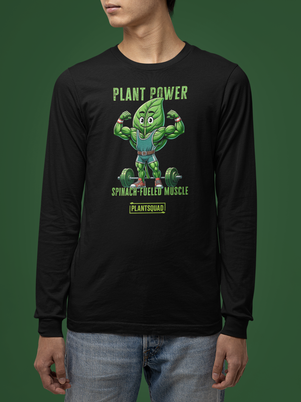 The Plantsquad Spinach "Plant Power Spinach Fueled Muscle" - Unisex Long Sleeve T-Shirt displays a cartoon spinach leaf character lifting weights. The text above reads "PLANT POWER" and below reads "SPINACH-FUELED MUSCLE." A small "PLANTSQUAD" logo is beneath the character. Perfect for fitness enthusiasts embracing a vegan lifestyle, the design is vibrant and green-themed.