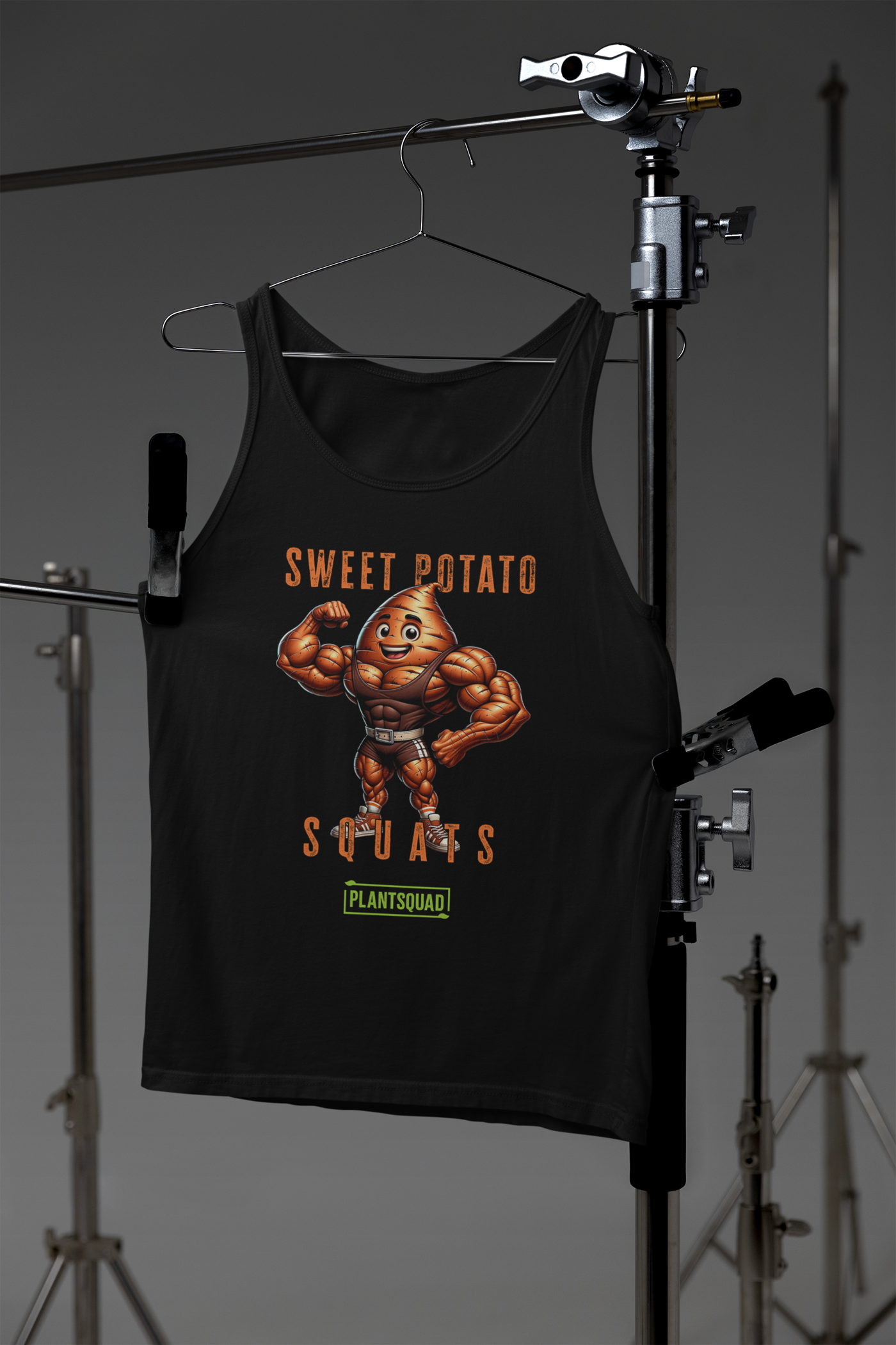 The Plantsquad Sweet Potato "Sweet Potato Squats" - Unisex Tank Top is a black vegan gym tank top featuring an illustration of a muscular anthropomorphic sweet potato flexing its arms. Above it, the text says "Sweet Potato Squats" and below it, a small green banner says "PlantSquad." Perfect for showcasing your plant-based lifestyle at the gym!