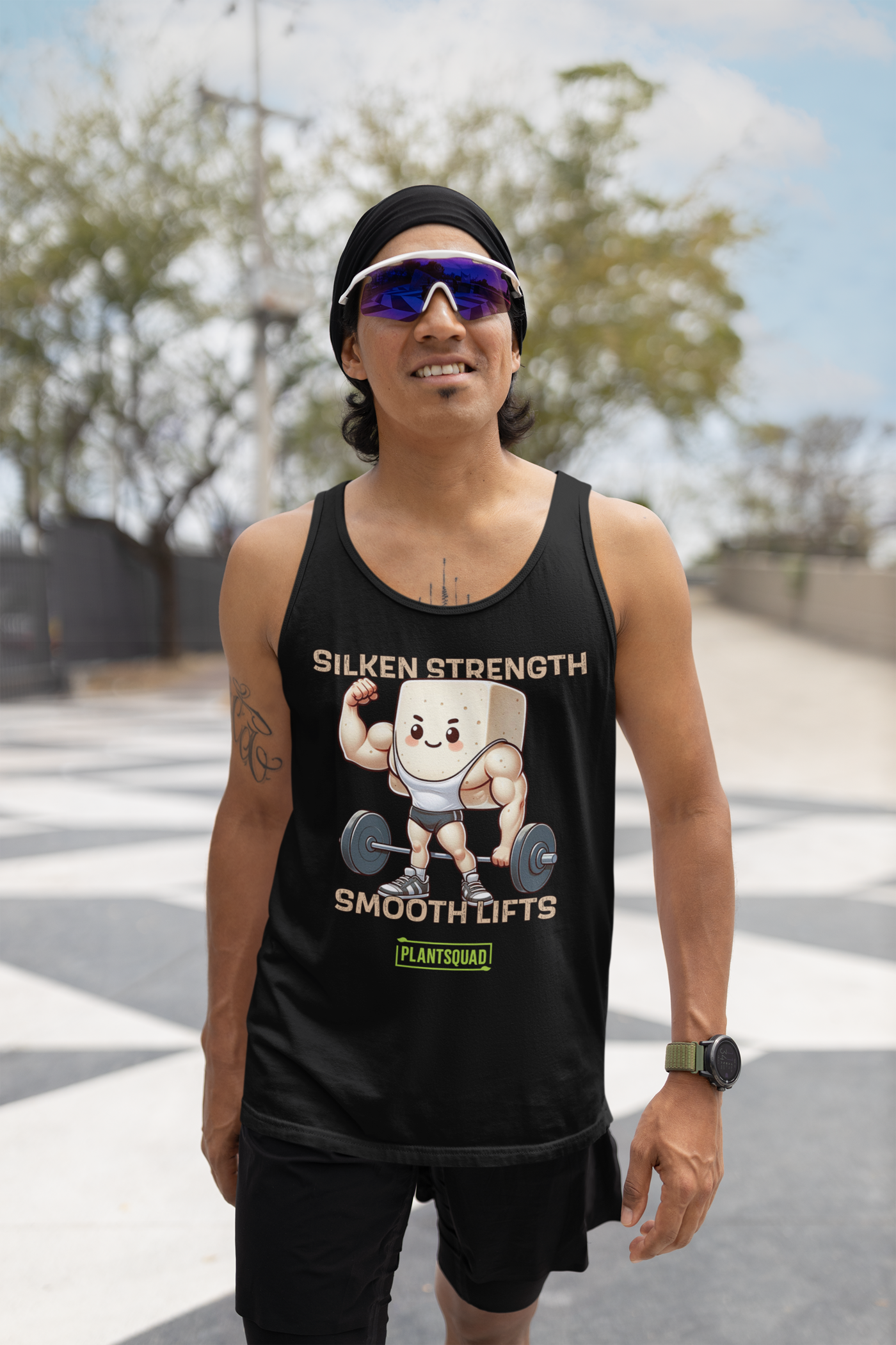 A black Plantsquad Tofu "Silken Strength Smooth Lifts" - Unisex Tank Top featuring a cartoon illustration of a muscular tofu block lifting a barbell. The text above reads "SILKEN STRENGTH," and below it says "SMOOTH LIFTS." Crafted from premium breathable fabric, this tank also has a small green logo with the text "PLANTSQUAD" for your vegan lifestyle.