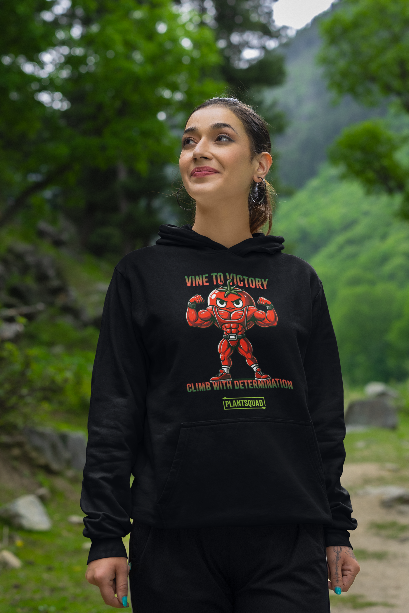 A Plantsquad Tomato "Vine To Victory Climb With Determination" - Unisex Hoodie featuring an illustration of a muscular, flexing tomato character with an angry expression. The text above reads "Vine to Victory" and below it says "Climb with Determination." A green box at the bottom contains the word "PLANTSQUAD," perfect for promoting a vegan lifestyle.