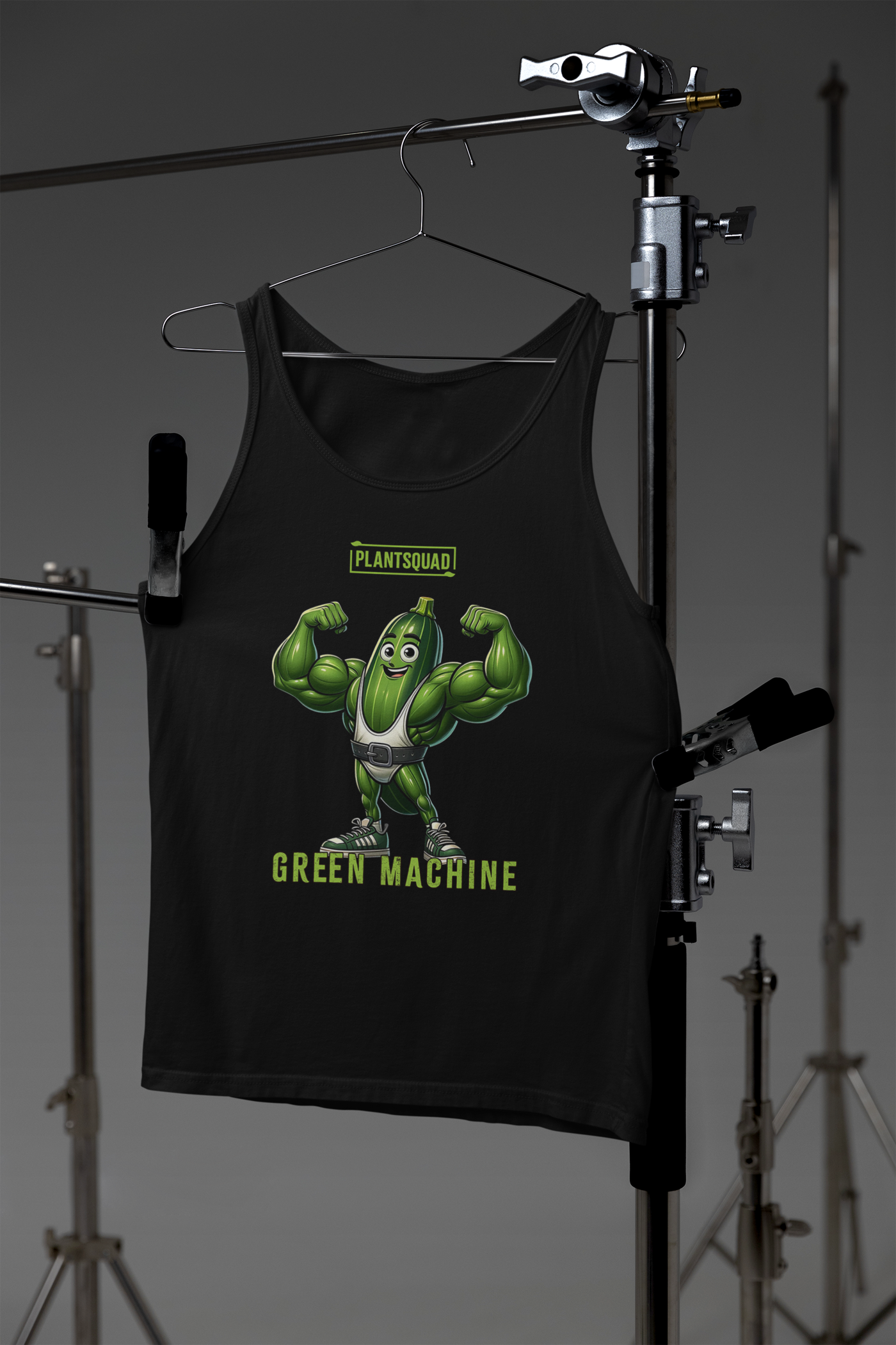 A black Plantsquad Zucchini "Green Machine" - Unisex Tank Top features a cartoon image of a muscular green vegetable character flexing its arms. Above the character, the text "PLANTSQUAD" is written, and below it, "GREEN MACHINE" is displayed. The character has a smiling face, sneakers, and a belt, perfect for promoting your plant-based lifestyle.